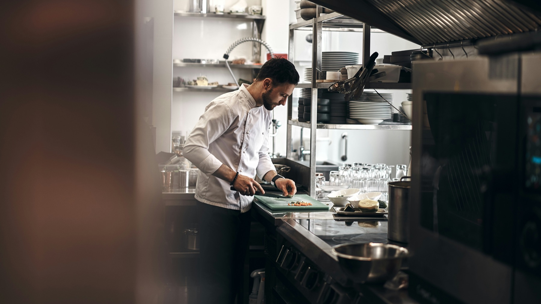 Cooks plating dishes at the pass in a small restaurant kitchen